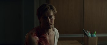 Movie still from “Department Q: A Conspiracy of Faith” (2016), directed by Hans Petter Moland – A shirtless man with blood all over his body; Medium shot, Over the shoulder angle