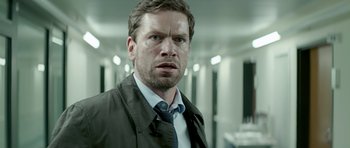 Movie still from “Department Q: A Conspiracy of Faith” (2016), directed by Hans Petter Moland – A person wearing a suit and tie; Close Up shot, Over the shoulder angle