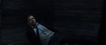 Movie still from “Department Q: A Conspiracy of Faith” (2016), directed by Hans Petter Moland – A man in a suit and tie laying on the ground; Medium shot, Low angle