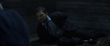 Movie still from “Department Q: A Conspiracy of Faith” (2016), directed by Hans Petter Moland – A man in a suit and tie sitting on the ground; Medium shot, High angle