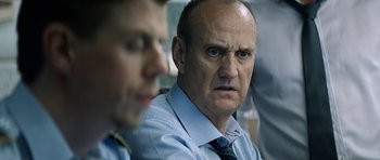 Movie still from “Department Q: A Conspiracy of Faith” (2016), directed by Hans Petter Moland – A man in a blue dress shirt and a man in a blue dress shirt and tie; Close Up shot, Over the shoulder angle