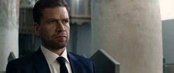 Movie still from “Department Q: A Conspiracy of Faith” (2016), directed by Hans Petter Moland – A person wearing a suit and tie; Close Up shot, Over the shoulder angle