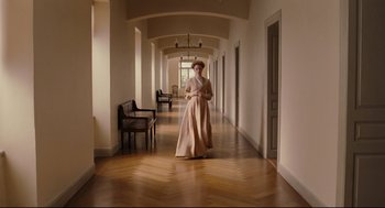 Movie still from “A Dangerous Method” (2011), directed by David Cronenberg – A woman in a long dress walking down a hall way; Wide shot, High angle
