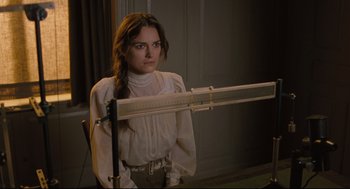 Movie still from “A Dangerous Method” (2011), directed by David Cronenberg – A woman in a white blouse is standing in front of a ruler; Medium shot, Over the shoulder angle