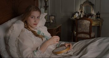 Movie still from “A Dangerous Method” (2011), directed by David Cronenberg – A young girl in a white dress is sewing a hoop; Medium shot, High angle