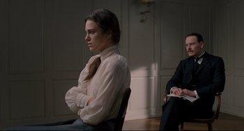 Movie still from “A Dangerous Method” (2011), directed by David Cronenberg – A woman sitting in front of a man in a room; Medium shot, Over the shoulder angle