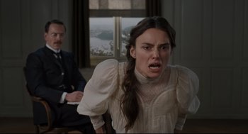 Movie still from “A Dangerous Method” (2011), directed by David Cronenberg – A woman in a white dress and a man in a black suit in a room; Medium shot, Low angle