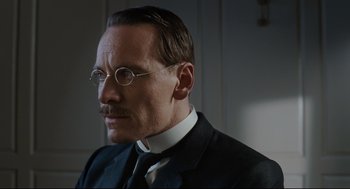 Movie still from “A Dangerous Method” (2011), directed by David Cronenberg – A man in a suit and tie wearing glasses; Close Up shot, Low angle