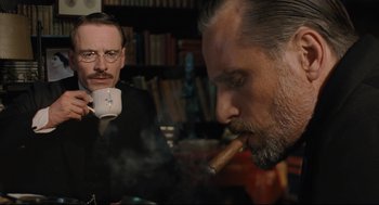 Movie still from “A Dangerous Method” (2011), directed by David Cronenberg – A man smoking a cigar while another man looks on; Close Up shot, Over the shoulder angle
