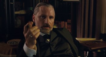Movie still from “A Dangerous Method” (2011), directed by David Cronenberg – An older man in a suit and tie holding a cigarette; Close Up shot, Low angle