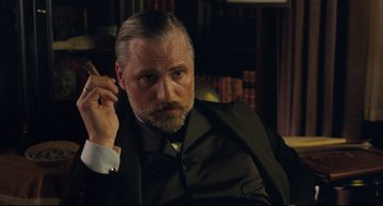 Movie still from “A Dangerous Method” (2011), directed by David Cronenberg – An older man in a suit and tie holding a cigarette; Close Up shot, Low angle