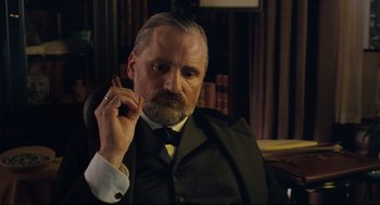 Movie still from “A Dangerous Method” (2011), directed by David Cronenberg – An older man in a suit and tie smoking a cigarette; Close Up shot, Low angle