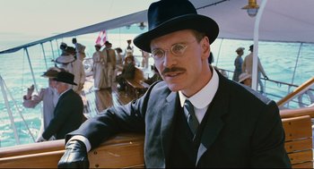 Movie still from “A Dangerous Method” (2011), directed by David Cronenberg – A man in a suit and a hat is posing for a picture; Medium shot, Low angle