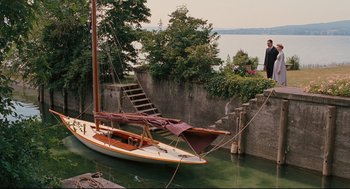 Movie still from “A Dangerous Method” (2011), directed by David Cronenberg – A man standing next to a boat in a body of water; Extreme Wide shot, High angle