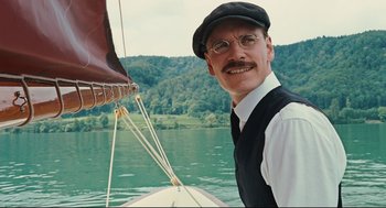 Movie still from “A Dangerous Method” (2011), directed by David Cronenberg – A man wearing a hat and glasses on a boat; Close Up shot, Low angle