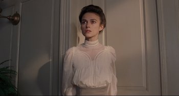 Movie still from “A Dangerous Method” (2011), directed by David Cronenberg – A woman in a white dress standing in front of a wall; Medium shot, Over the shoulder angle