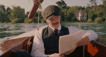 Movie still from “A Dangerous Method” (2011), directed by David Cronenberg – A man sitting in a boat on a lake reading; Medium shot, Low angle