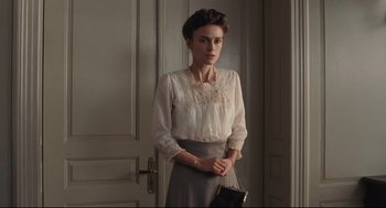 Movie still from “A Dangerous Method” (2011), directed by David Cronenberg – A woman standing in front of a door holding a purse; Medium shot, Over the shoulder angle