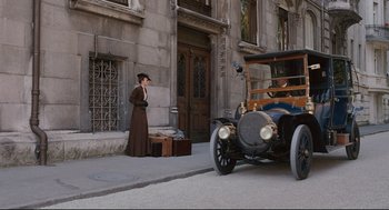 Movie still from “A Dangerous Method” (2011), directed by David Cronenberg – A woman in a brown dress standing next to a car; Wide shot, Low angle