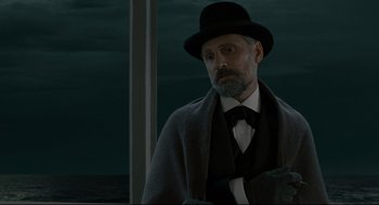 Movie still from “A Dangerous Method” (2011), directed by David Cronenberg – A man with a beard wearing a black hat; Medium shot, Low angle