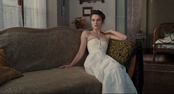 Movie still from “A Dangerous Method” (2011), directed by David Cronenberg – A woman in a white dress sitting on a couch; Medium shot, Over the shoulder angle