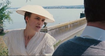 Movie still from “A Dangerous Method” (2011), directed by David Cronenberg – A woman wearing a white hat sitting next to a body of water; Medium shot, Over the shoulder angle