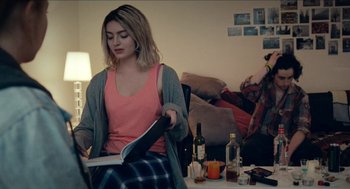 Movie still from “A Date for Mad Mary” (2016), directed by Darren Thornton – A woman sitting at a table reading a book; Medium shot, Over the shoulder angle