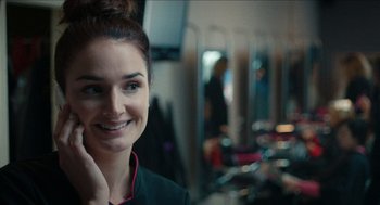 Movie still from “A Date for Mad Mary” (2016), directed by Darren Thornton – A woman smiling for the camera in front of a mirror; Close Up shot, Over the shoulder angle