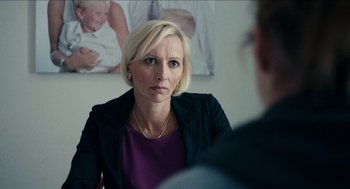 Movie still from “A Date for Mad Mary” (2016), directed by Darren Thornton – A woman sitting in front of a man in front of a picture; Close Up shot, Over the shoulder angle