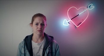Movie still from “A Date for Mad Mary” (2016), directed by Darren Thornton – A woman standing in front of a neon heart; Medium shot, Over the shoulder angle