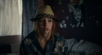 Movie still from “A Date for Mad Mary” (2016), directed by Darren Thornton – A woman wearing a straw hat in a room; Close Up shot, Over the shoulder angle