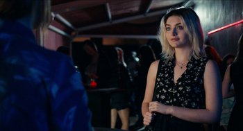 Movie still from “A Date for Mad Mary” (2016), directed by Darren Thornton – A woman standing in front of other people in a room; Medium shot, Over the shoulder angle