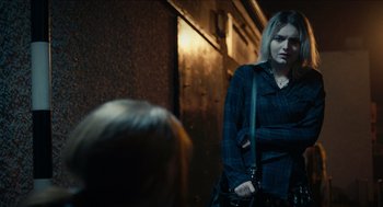 Movie still from “A Date for Mad Mary” (2016), directed by Darren Thornton – A woman is holding a purse while standing next to another woman; Medium shot, Over the shoulder angle