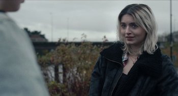 Movie still from “A Date for Mad Mary” (2016), directed by Darren Thornton – A young woman standing in front of a bush; Close Up shot, Over the shoulder angle