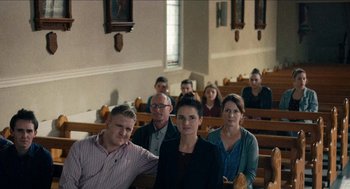 Movie still from “A Date for Mad Mary” (2016), directed by Darren Thornton – A group of people sitting in front of pews in a church; Wide shot, High angle
