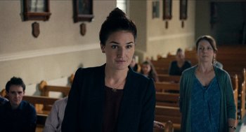 Movie still from “A Date for Mad Mary” (2016), directed by Darren Thornton – A woman is standing in front of a group of pews; Close Up shot, Over the shoulder angle