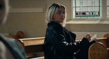 Movie still from “A Date for Mad Mary” (2016), directed by Darren Thornton – A woman sitting on a bench in front of a window; Close Up shot, Over the shoulder angle