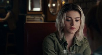 Movie still from “A Date for Mad Mary” (2016), directed by Darren Thornton – A woman sitting at a table with a glass of water; Close Up shot, Over the shoulder angle
