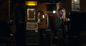 Movie still from “A Date for Mad Mary” (2016), directed by Darren Thornton – A woman sitting at a table in a restaurant; Medium shot, Over the shoulder angle