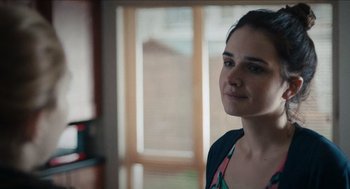 Movie still from “A Date for Mad Mary” (2016), directed by Darren Thornton – A woman standing in front of a window looking to her left; Close Up shot, Over the shoulder angle