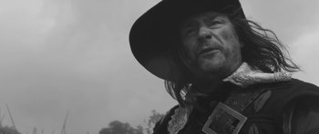 Movie still from “A Field in England” (2013), directed by Ben Wheatley – A person wearing a hat; Close Up shot, Over the shoulder angle