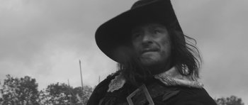 Movie still from “A Field in England” (2013), directed by Ben Wheatley – A black and white photo of a man wearing a hat; Close Up shot, Over the shoulder angle