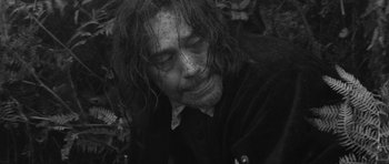 Movie still from “A Field in England” (2013), directed by Ben Wheatley – A black and white photo of a man with long hair; Close Up shot, Low angle