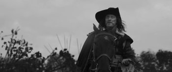 Movie still from “A Field in England” (2013), directed by Ben Wheatley – A man wearing a cowboy hat is riding a horse; Medium shot, Low angle