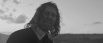 Movie still from “A Field in England” (2013), directed by Ben Wheatley – A black and white photo of a man with long hair; Close Up shot, Low angle