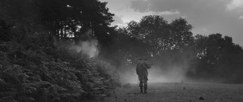 Movie still from “A Field in England” (2013), directed by Ben Wheatley – A man standing in a field near a tree; Wide shot, Over the shoulder angle