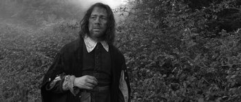 Movie still from “A Field in England” (2013), directed by Ben Wheatley – Black and white photograph of a man in medieval garb; Medium shot, Low angle