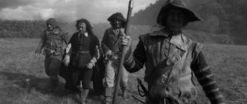 Movie still from “A Field in England” (2013), directed by Ben Wheatley – A group of men standing next to each other; Medium shot, Low angle
