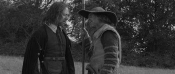 Movie still from “A Field in England” (2013), directed by Ben Wheatley – Two men in medieval garb talking to each other; Medium shot, Over the shoulder angle