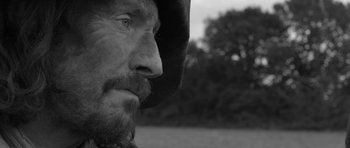 Movie still from “A Field in England” (2013), directed by Ben Wheatley – A person with a beard; Close Up shot, Over the shoulder angle